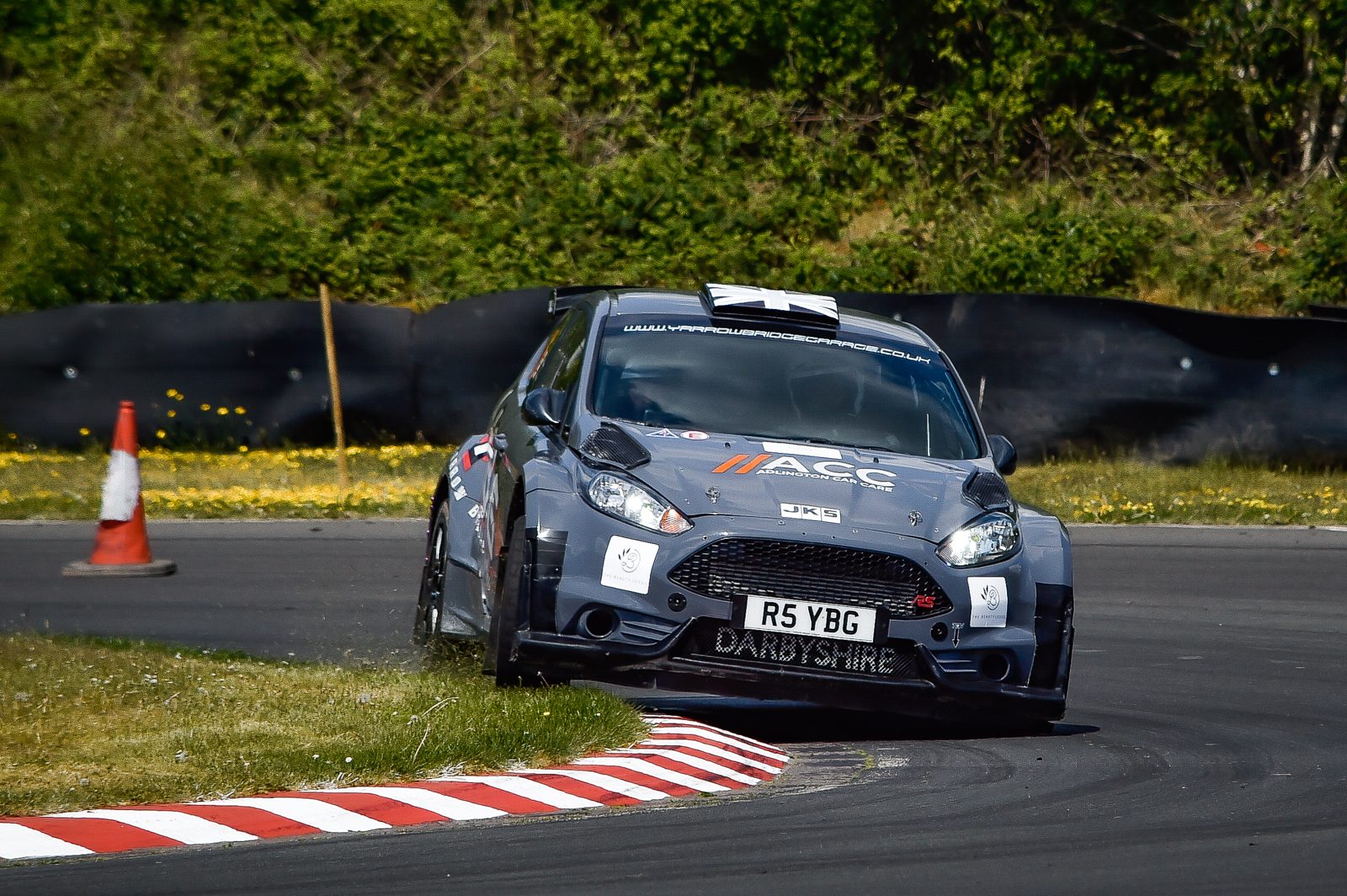 Grey Ford Fiesta rally car branded ACC Adlington Car Care on a paved stage