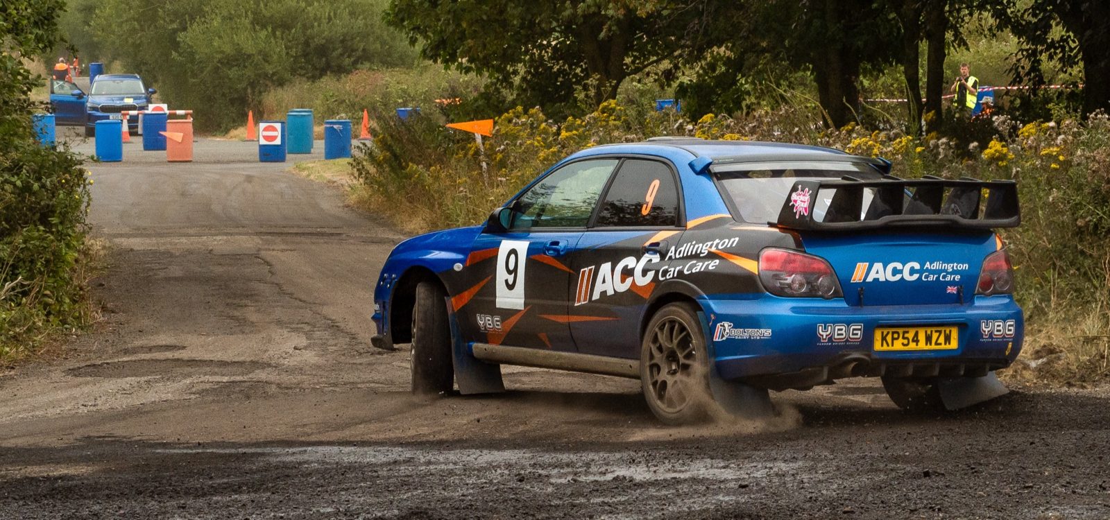 Wide shot of the Adlington Car Care Subaru on a dirt rally stage